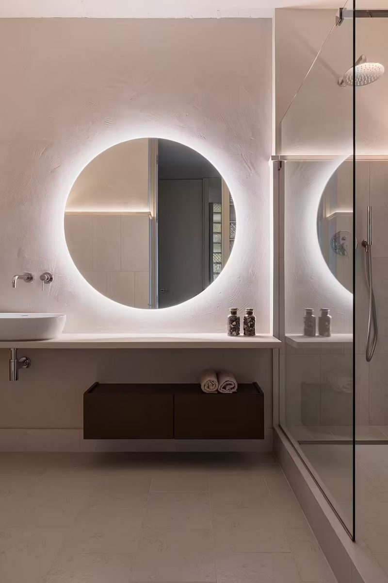 Een mooie grote ronde spiegel met verlichting boven de wastafel, in een moderne badkamer ontworpen door Tetiana Denysenko Interior Design.