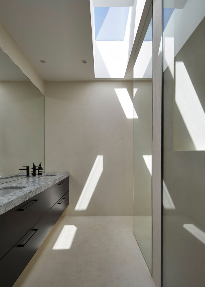 De naadloze microcement wanden en vloeren geven deze badkamer een stijlvolle en minimalistische look, ontworpen door FGR Architects.