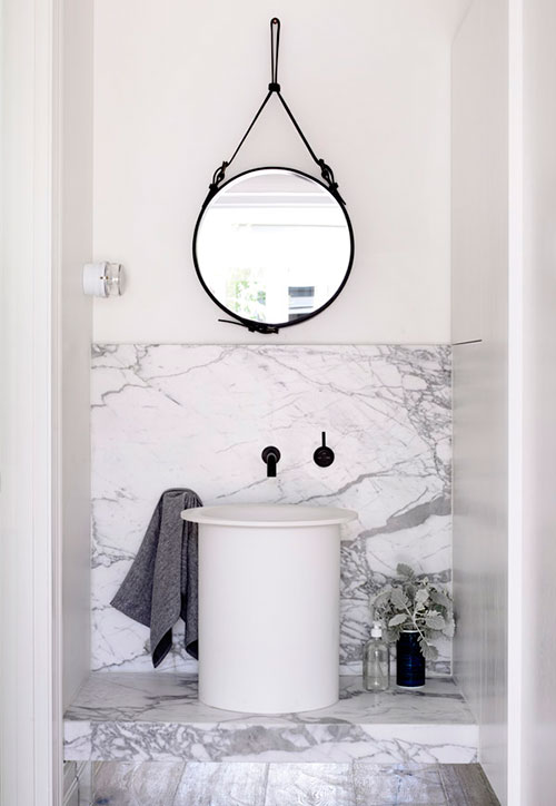 Ronde spiegel boven hoge design wastafel op marmeren blad