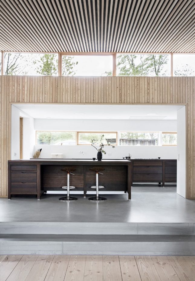 splitlevel open keuken met beton cire vloer, houten wand- en palfondbekleding en charcoal houten keukenkasten