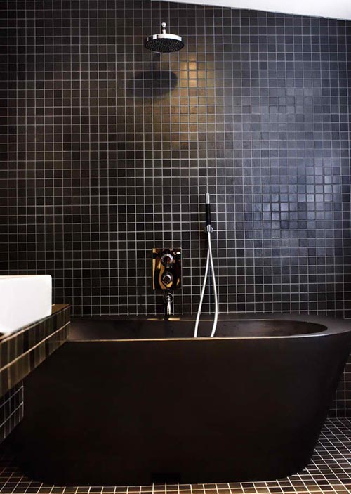 Vrijstaand zwart bad in badkamer met zwarte tegels