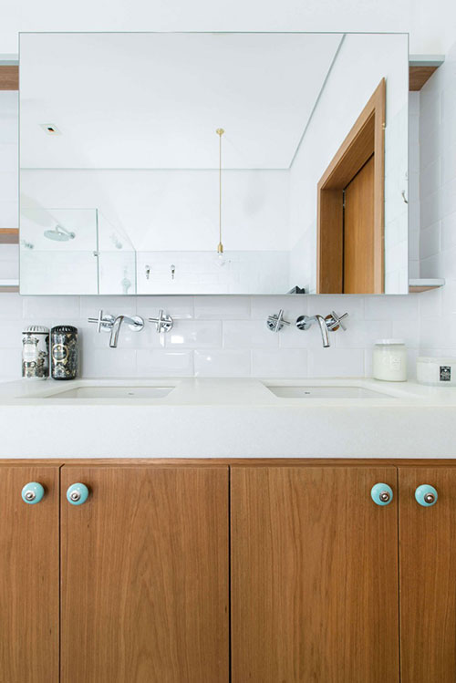 Grote wandspiegel boven houten badkamermeubel met dubbele wastafels