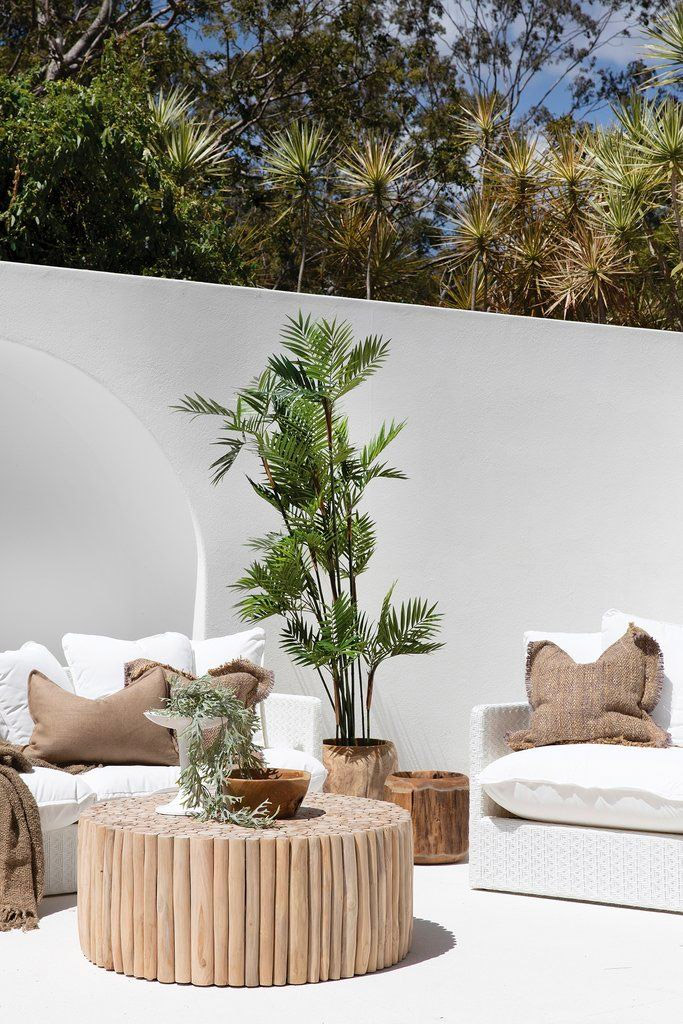 Houten meubels zijn een musthave in elke Ibiza tuin. In deze mooie tuin, met witte muren en vloer, zijn witte banken gecombineerd met een mooie ronde boomstam salontafel. De tafel is hier verkrijgbaar!