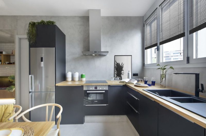 Stoere betonstuc keuken achterwand én vloer, gecombineerd met een moderne zwarte keuken.