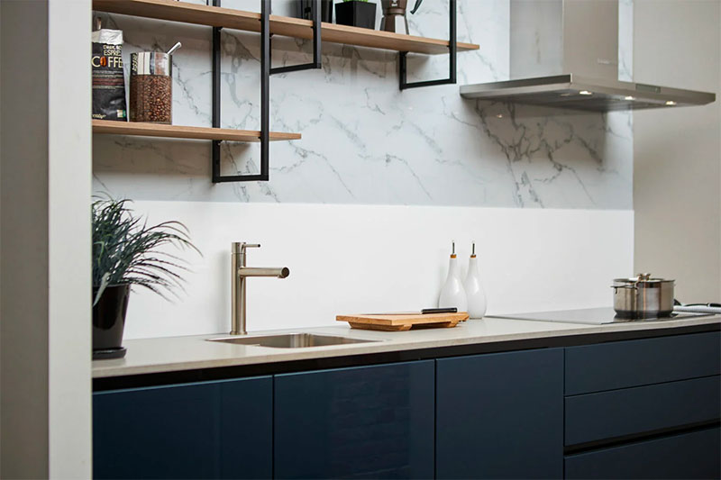 Donkerblauwe keuken en een witte plexiglas keuken achterwand. Hier verkrijgbaar.