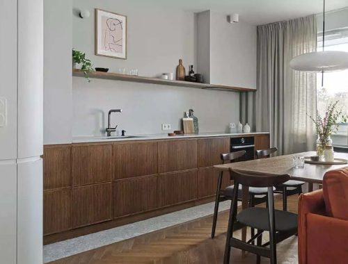 Raca Architects koos voor deze mooie open keuken voor een strook natuurstenen tegels als keukenvloer, gecombineerd met de visgraat houten vloer in de eethoek en woonkamer.