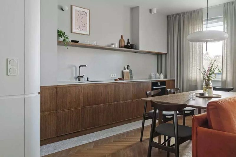 Raca Architects koos voor deze mooie open keuken voor een strook natuurstenen tegels als keukenvloer, gecombineerd met de visgraat houten vloer in de eethoek en woonkamer.