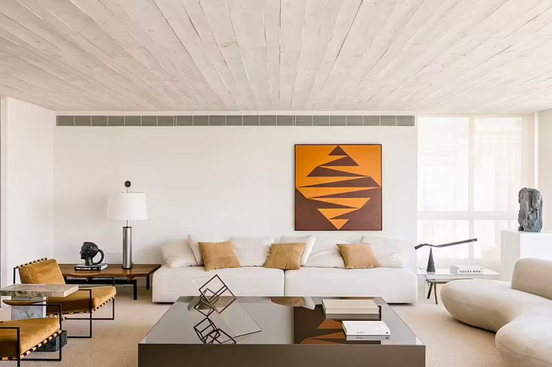 Studio Arthur Casas koost voor deze woonkamer voor luxe meubels van gerenommeerde ontwerpers, zoals de Anette fauteuil, de Adobe 2-tafel van Guilherme Wentz; een lamp van Sergio Rodrigues; en een bijzettafel van Lucas Recchia.