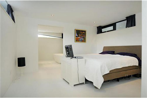 Open badkamer ensuite in witte slaapkamer van woonboot