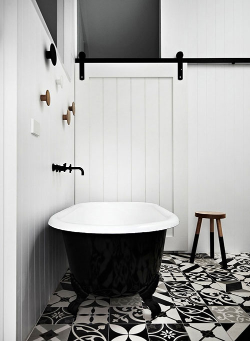 Leuke zwart witte patchwork vloertegels en vrijstaand zwart bad op pootjes