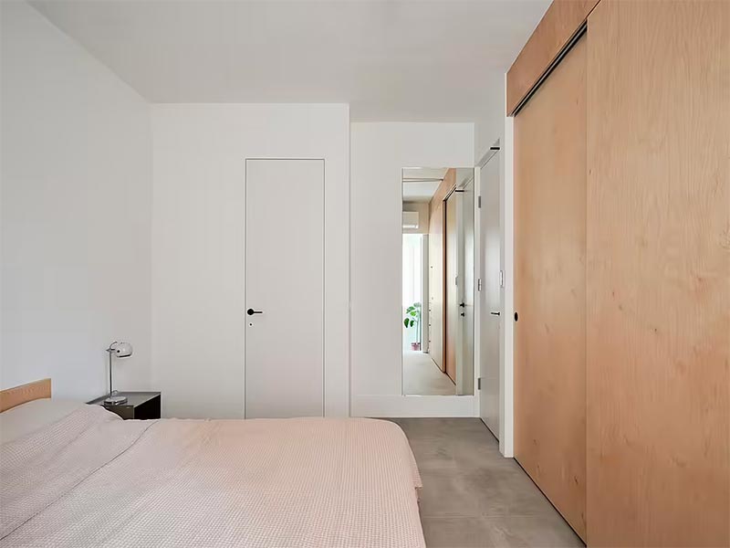 Deze minimalistische slaapkamer is ontworpen door St Design Studio, waar de blinde deur opgaat in de strakke witte muren. | Fotografie: Suiyu