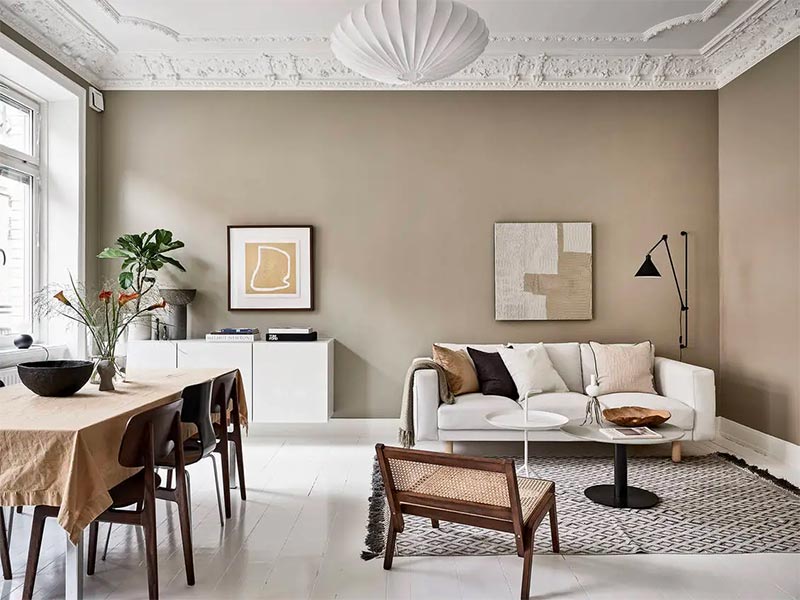 Een wit geverfde houten vloer, gecombineerd met een warme zandkleur muur in een super leuke woonkamer.