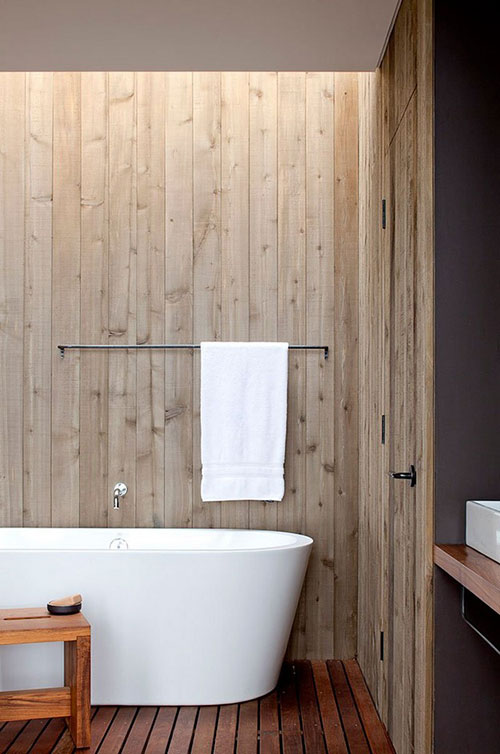 Modern vrijstaand bad in natuurlijke badkamer met houten vloer en wanden