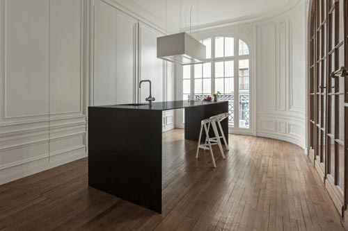 Hangende witte afzuigkap boven minimalistisch zwart kookeiland Hangende witte afzuigkap boven minimalistisch zwart kookeiland