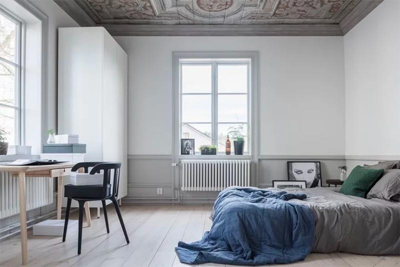 Super mooie plafondschildering aan het houten plafond van een lichte Scandinavische slaapkamer.