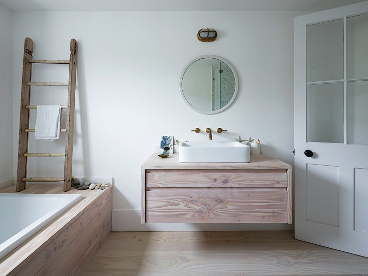Badkamer met houten vloer, badkamermeubel en badombouw