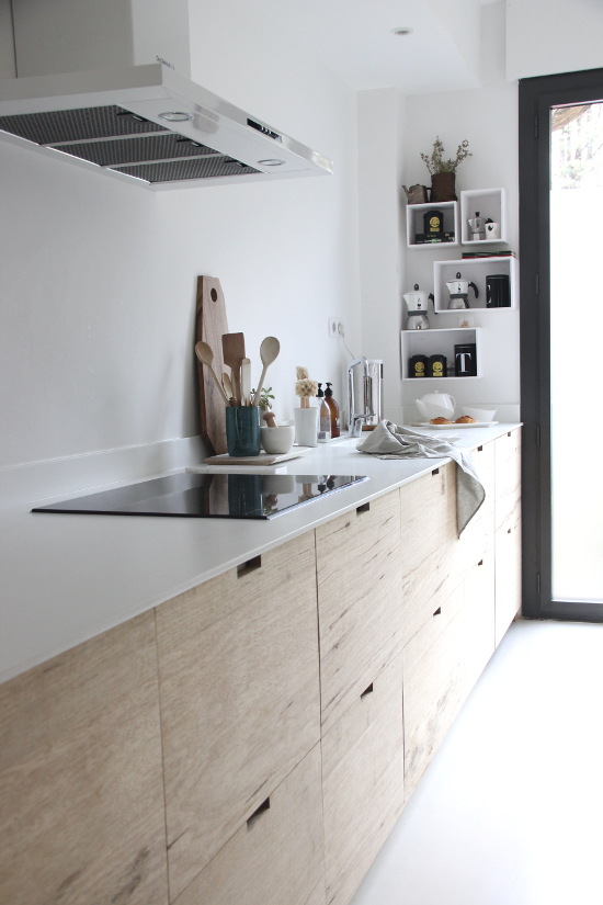De strakke witte gestuukte spatwand staat prachtig in deze lichte moderne keuken met witte keukenblad en houten kasten. Klik hier voor meer foto's.