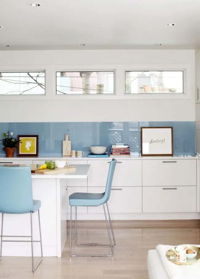 Moderne witte keuken met een mooie blauwe glazen spatwand over de hele breedte van de muur.
