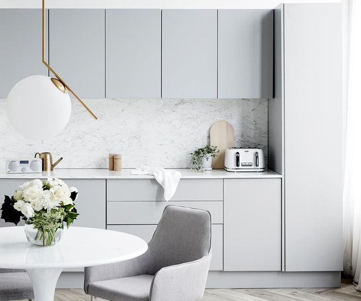 Een super mooie combinatie in deze licht Scandinavische keuken van lichtgrijze keukenkasten en carrara wit marmeren werkblad en spatwand. Klik hier voor meer foto's.