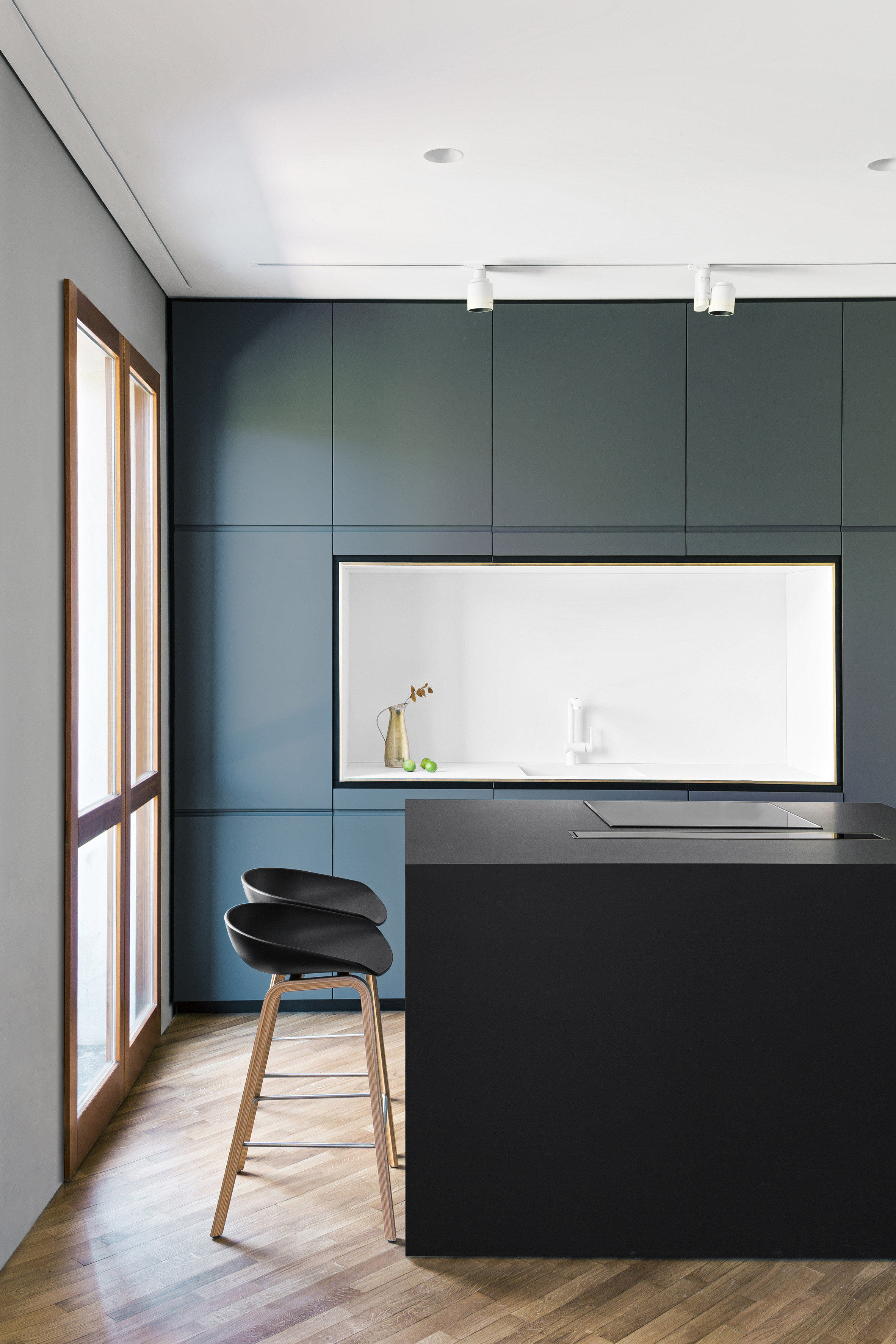 Strakke moderne keuken met blauwe wandkast en zwart kookeiland