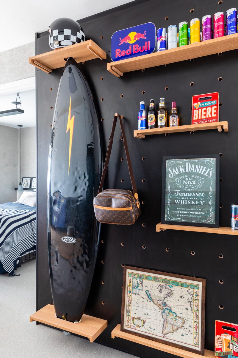 Concretize Interiores heeft voor dit kleine loft appartement een stoere gaatjesboard muur ontworpen waar onder andere een groot surfboard verticaal is opgehangen.