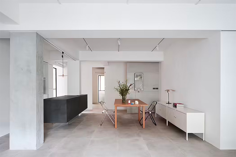 Ook een tegelvloer kan je zonder plinten afwerken. Dat is heel mooi te zien in dit appartement, ontworpen door St Design Studio, waar betonlook tegels gecombineerd zijn met strakke witte wanden. | Fotografie: Suiyu