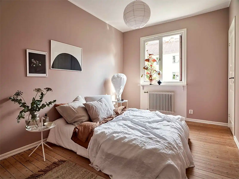 Een stijlvolle ton sur ton slaapkamer met oud roze muren als basis, aangevuld met lichte en donkere roze tinten als beddengoed.