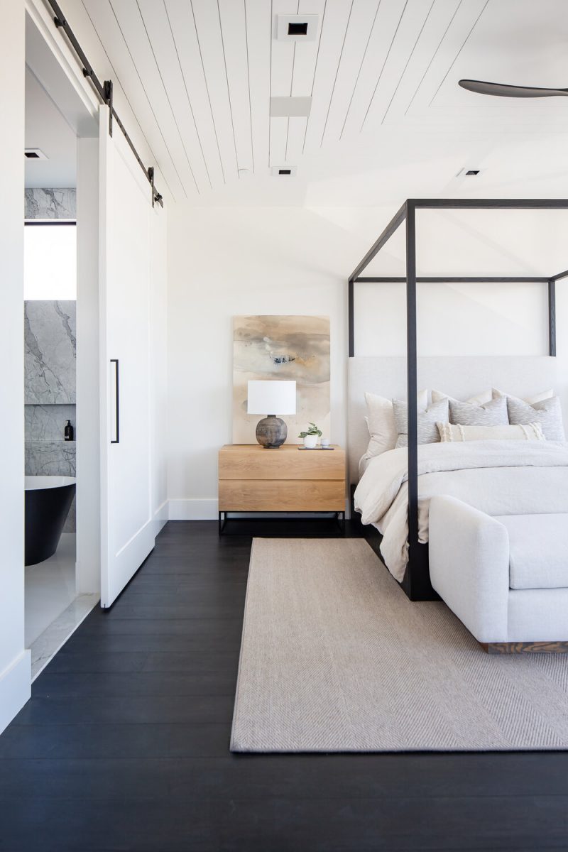 In deze slaapkamer, ontworpen door Booke Wagner Design is er gekozen voor een donkere houten vloer, maar onder het bed vind je een mooi groot vloerkleed.