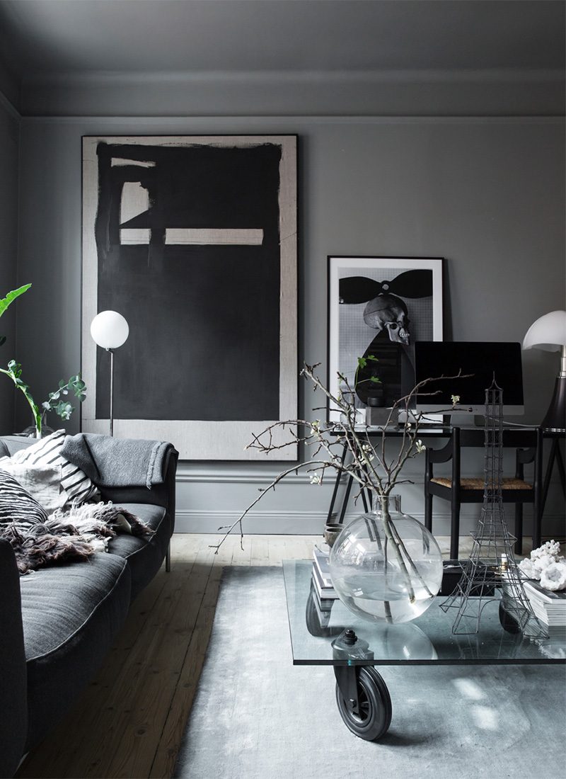 Zweedse stylist Lotta heeft in haar mooie woonkamer een super grote schilderij aan de donkergrijze muur opgehangen, gecombineerd met een kleine schilderij ernaast.