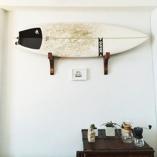 Hier is een oude surfboard aan de muur opgehangen met behulp van mooie houten houders.