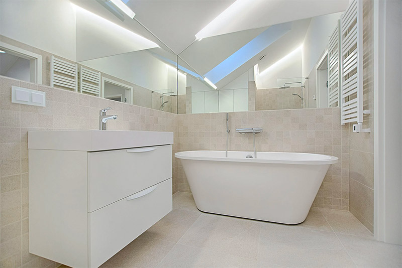 In deze badkamer zijn twee wanden bekleed met spiegels op maat, zowel boven de wastafel als boven het bad.