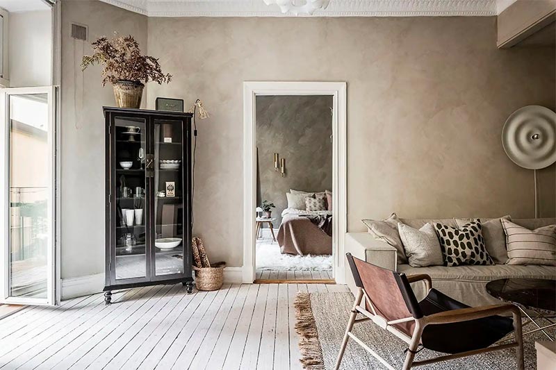 De limewash muren in een beige kleurtint zijn in deze woonkamer gecombineerd met andere mooie aardetinten voor een knusse sfeer.