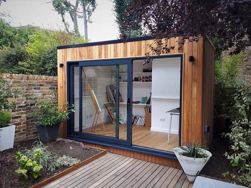 Dit kleine tuinhuisje met glazen schuifwand is ingericht als een atelier.