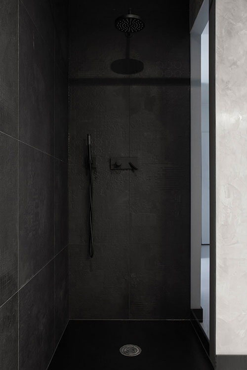 Moderne inloopdouche met grote antraciet tegels en zwarte douche