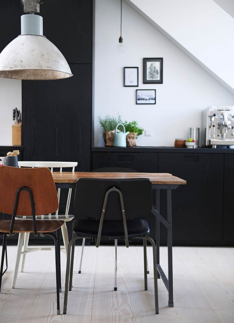 Grote industriële hanglamp boven vintage eettafel en stoelen Grote industriële hanglamp boven vintage eettafel en stoelen